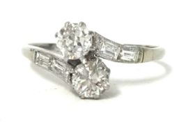 A two stone diamond cross over ring set with further emerald cut diamonds to the shoulders set in