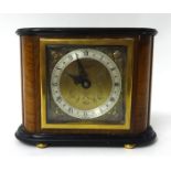 An Elliott mantle clock in walnut case, the square dial with gilt metal spandrels, on bun feet, with