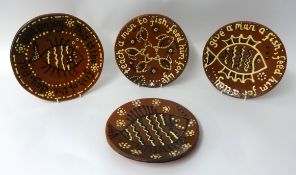 Four earthenware and slip decorated 'Fish' plates with stylised decoration and motto's including '