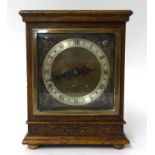 An Elliott mantle clock in oak case, the square dial with gilt metal spandrels, on bun feet, with