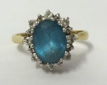 A 9ct yellow and white gold cluster ring set with single oval blue Topaz, surrounded by 16 brilliant