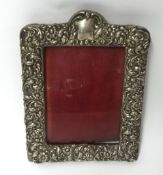 A silver photo frame with embossed decoration of stylised flowers, 20cm x 15cm