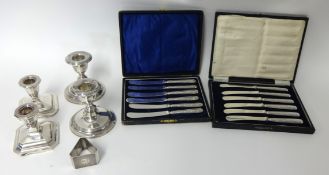 Two pairs of short candlesticks, set of six butter knives with silver handles in fitted case by