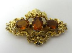 A Victorian three stone Citrine brooch, set in a yellow metal scroll work frame