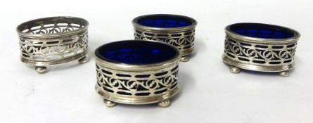 A set of four silver and pierced table salts three with blue glass liners