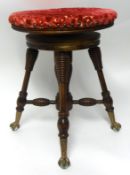 Late Victorian revolving piano stool with turned legs, eagle style feet with glass claws