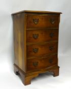 A small reproduction serpentine yew wood veneered chest of four drawers, 46cm high
