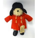 A Paddington Bear soft toy with red coat and label 40cm tall
