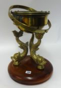 A brass binnacle, 42cm x 32cm base on 3 brass dolphins seated on thick teak round base