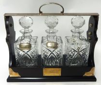 A three bottle glass Tantalus with presentation plaque (modern)