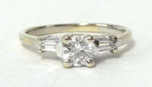 A diamond round cut solitaire ring, with a pair of baguette cut diamonds on the shoulders set in