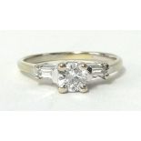 A diamond round cut solitaire ring, with a pair of baguette cut diamonds on the shoulders set in