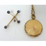 15ct gold cross set with blue gem stones, also a yellow metal circular locket pendant on link chain,