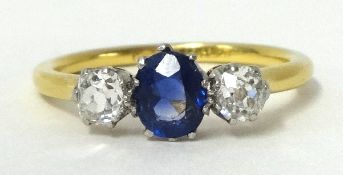 An 18ct gold and platinum three stone ring set with single sapphire and two old cut diamonds, size