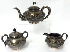 A Chinese silver tea set Hung Chong Shanghai decorated with a dragon in relief and bamboo handles