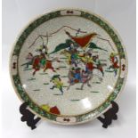 A Chinese crackle glazed wall plate, decorated with warriors on horseback, diameter 40cm.