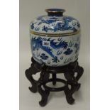 A Chinese reproduction blue and white jar and cover on a carved wood stand