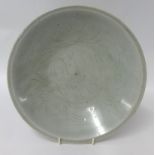 A Chinese celadon glazed pottery dish, of circular form with incised decoration, diameter 27cm .