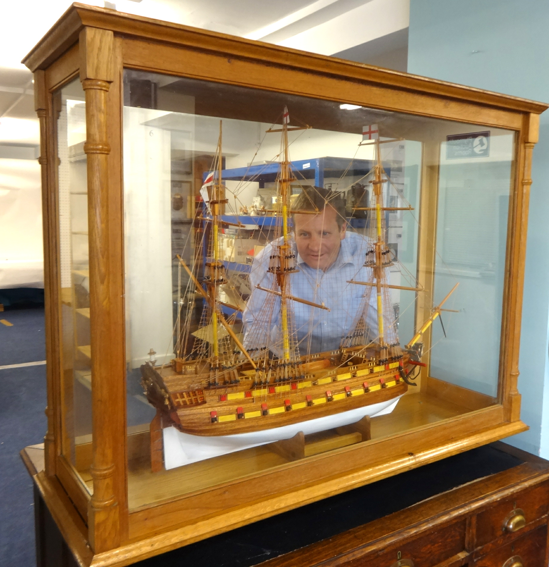 A large Man of War model ship, approx 100cm wide x 70cm tall. in a glazed oak display cabinet.