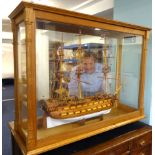 A large Man of War model ship, approx 100cm wide x 70cm tall. in a glazed oak display cabinet.