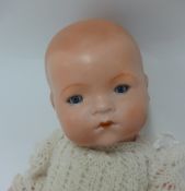 An Armand Marseille baby doll with fixed blue glass eyes, closed mouth and jointed composition body,