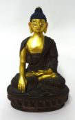 A gilded bronze figure of a Buddha, seated in dhyanasana on a lotus wearing a sanghati draped over