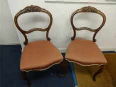 A pair of Victorian balloon back dining chairs with cabriole legs.