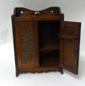 A carved oak smokers cabinet.