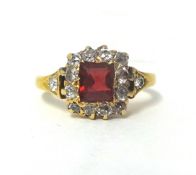 A red spinel and diamond cluster ring, set with an emerald cut stone bordered by old cut stones,