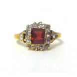 A red spinel and diamond cluster ring, set with an emerald cut stone bordered by old cut stones,