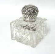 A Victorian silver mounted cut glass inkwell, London 1898, the floral embossed and chased cover,