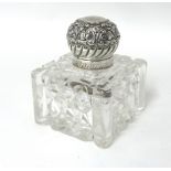 A Victorian silver mounted cut glass inkwell, London 1898, the floral embossed and chased cover,