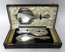 A silver five piece dressing table set, Birmingham 1929, cased and a silver mounted glove