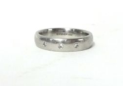 A platinum and diamond band ring, rub over set with three brilliant cut diamonds, size K, weight 7