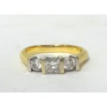 An 18ct gold three stone diamond ring, claw set with a Princess cut stone weighing approximately 0.