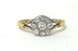 An 18ct gold and diamond cluster ring, claw set with an old cut stone bordered by smaller stones,
