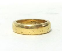 A wedding band, stamped 22K, size M, weight 10 grams.