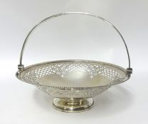 A silver swing handle cake basket, London 1914, of circular form with a pierced border, raised on