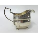 A George III Irish silver milk jug, Dublin 1813, with bright-cut engraved decoration, raised on four