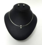 An 18ct white gold single stone diamond and Tahitian black pearl necklace, the collet set stone