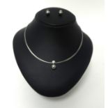 An 18ct white gold single stone diamond and Tahitian black pearl necklace, the collet set stone