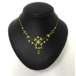 A Victorian gold, peridot and half pearl set necklace, the graduated openwork scroll front