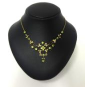 A Victorian gold, peridot and half pearl set necklace, the graduated openwork scroll front