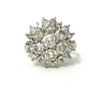 A white gold and diamond cluster ring, claw set with a brilliant cut stone, bordered by six of a