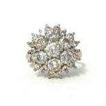 A white gold and diamond cluster ring, claw set with a brilliant cut stone, bordered by six of a