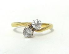 An 18ct gold and two stone diamond ring, twist claw set with old cut brilliant stones of