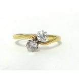 An 18ct gold and two stone diamond ring, twist claw set with old cut brilliant stones of