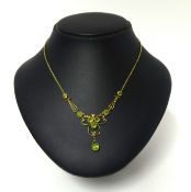 A Victorian gold and peridot necklace, the openwork scroll front milligrain collet set with mixed