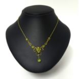 A Victorian gold and peridot necklace, the openwork scroll front milligrain collet set with mixed