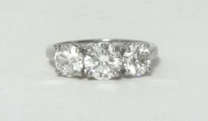A platinum and diamond three stone ring, claw set with brilliant cut stones, the central stone